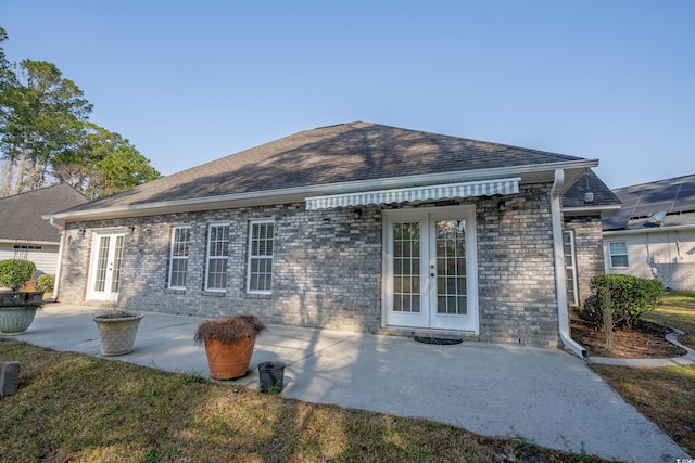 rear view of property with brick siding, french doors, a shingled roof, and a patio