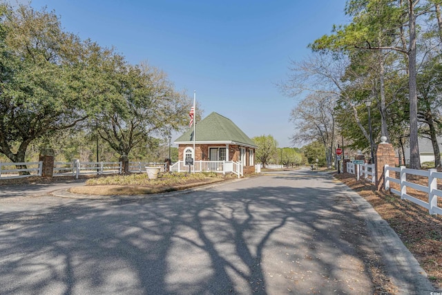 view of front of house with a fenced front yard, covered porch, aphalt driveway, and brick siding