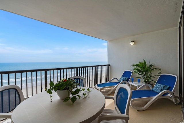 balcony with outdoor dining space and a water view