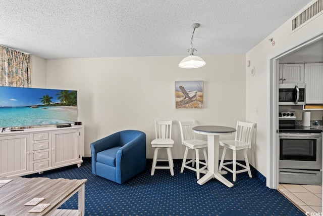 interior space featuring tile patterned floors, visible vents, decorative light fixtures, a textured ceiling, and appliances with stainless steel finishes