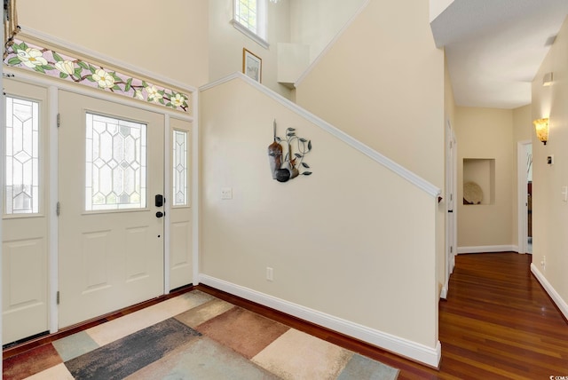 entryway with baseboards, dark wood-style floors, and a towering ceiling