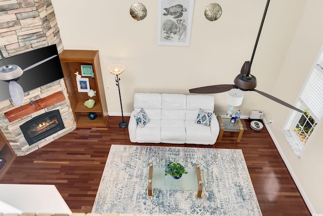 living room with baseboards, a ceiling fan, wood finished floors, and a fireplace