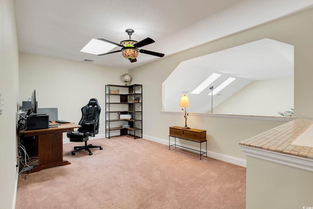 office with a skylight, a ceiling fan, baseboards, and carpet floors