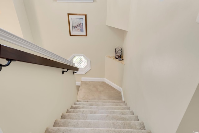 stairway featuring baseboards and carpet floors