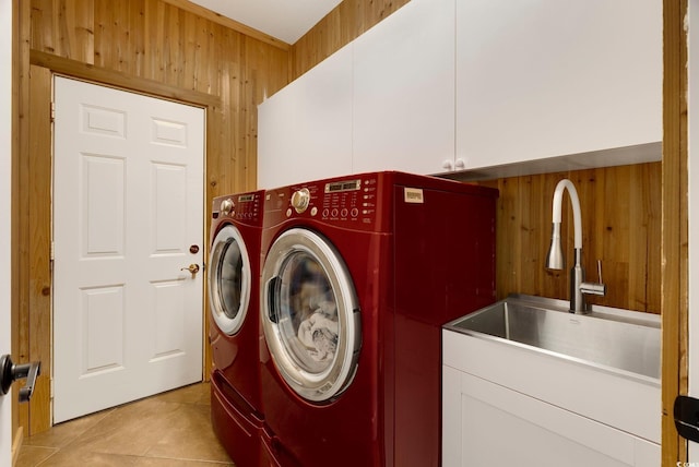 laundry area with washer and dryer, a sink, cabinet space, wooden walls, and light tile patterned flooring