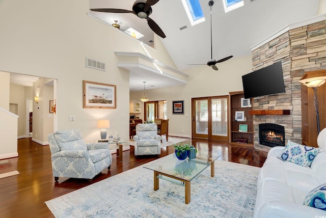 living room with visible vents, a skylight, a ceiling fan, and wood finished floors