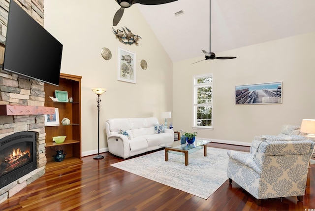 living area featuring visible vents, high vaulted ceiling, wood finished floors, a stone fireplace, and ceiling fan