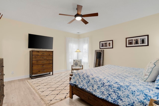 bedroom featuring light wood-style flooring, visible vents, baseboards, and ceiling fan