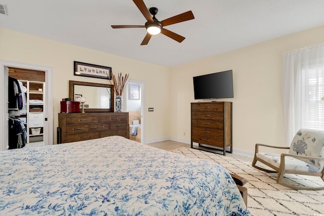 bedroom with visible vents, a walk in closet, light wood-style floors, baseboards, and ceiling fan