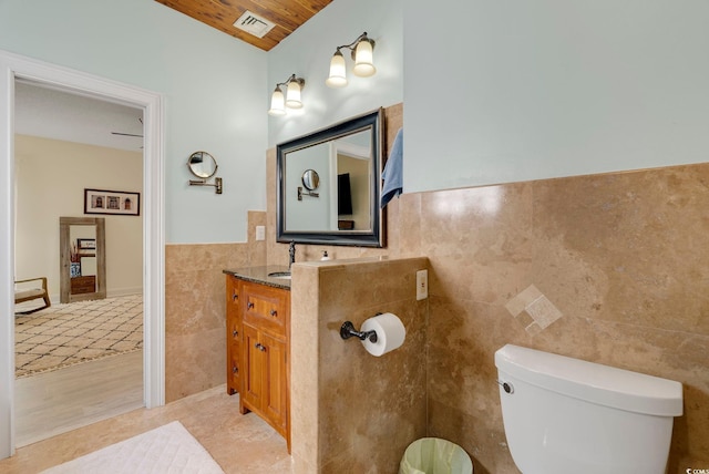 half bath featuring vanity, visible vents, tile walls, toilet, and tile patterned floors