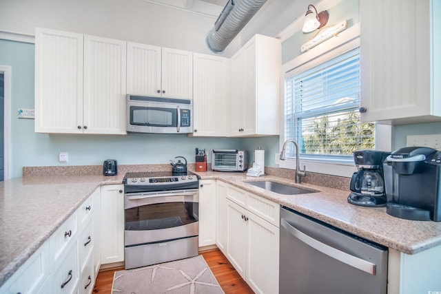 162 Norris Dr, Pawleys Island, SC 29585 - kitchen with a sink, wood finished floors, stainless steel appliances, white cabinets, and a toaster