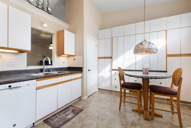 kitchen with white cabinetry, a sink, dishwasher, dark countertops, and backsplash