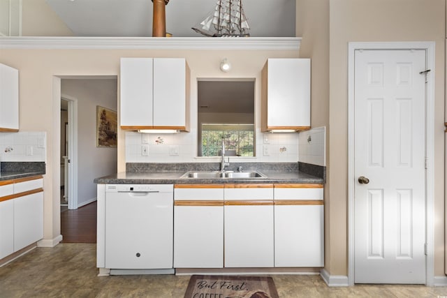 kitchen featuring dark countertops, dishwasher, white cabinetry, and a sink