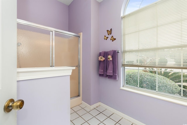 bathroom with a shower with door, tile patterned floors, and baseboards