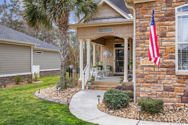 entrance to property with stone siding, a lawn, and covered porch