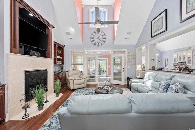 living room with visible vents, ceiling fan, a fireplace, high vaulted ceiling, and dark wood-style flooring