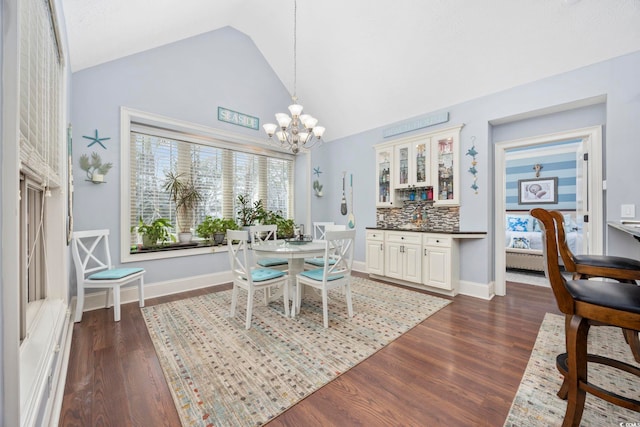 dining space featuring baseboards, lofted ceiling, a notable chandelier, and dark wood-type flooring