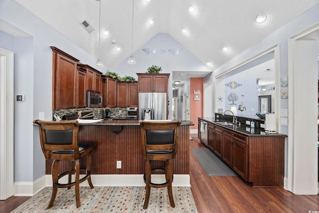 kitchen with visible vents, a breakfast bar, a peninsula, stainless steel appliances, and dark wood-style flooring