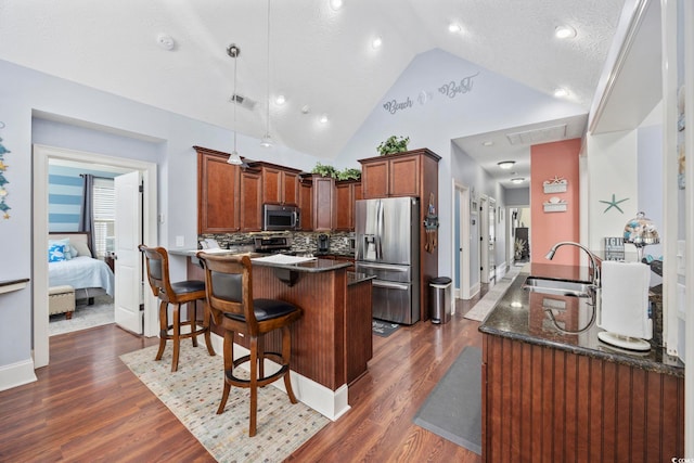 kitchen featuring visible vents, a kitchen bar, appliances with stainless steel finishes, a peninsula, and a sink