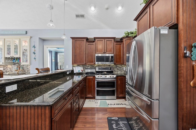 kitchen featuring visible vents, backsplash, dark stone countertops, appliances with stainless steel finishes, and a peninsula