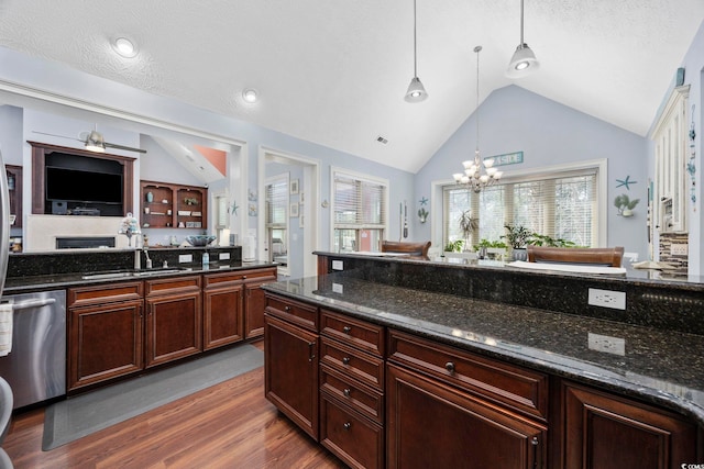 kitchen with wood finished floors, a sink, vaulted ceiling, stainless steel dishwasher, and a notable chandelier