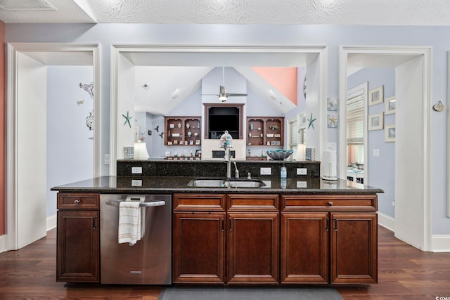 kitchen with a sink, dishwasher, dark wood-style floors, and dark stone countertops