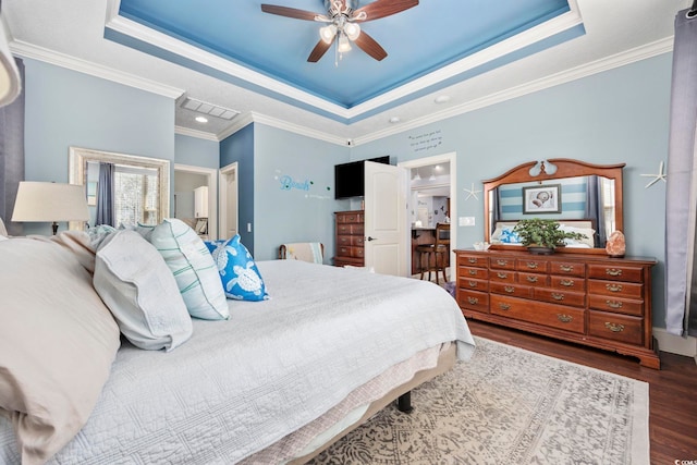 bedroom with a raised ceiling, wood finished floors, visible vents, and ornamental molding