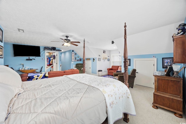 bedroom with a walk in closet, light carpet, a textured ceiling, lofted ceiling, and ceiling fan