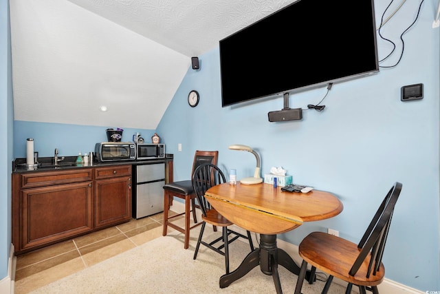 dining area featuring light tile patterned floors, baseboards, wet bar, a toaster, and vaulted ceiling