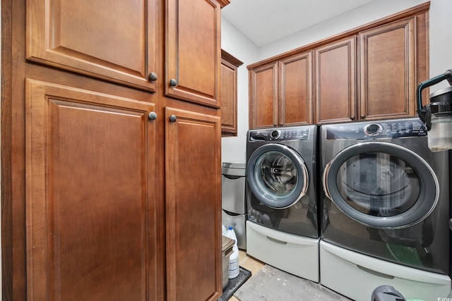 clothes washing area with washing machine and dryer and cabinet space