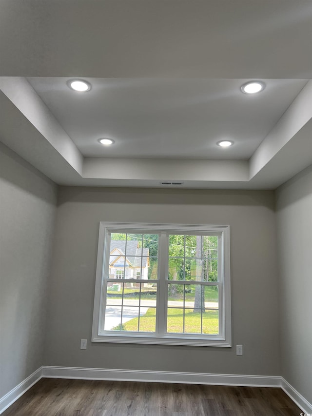 spare room featuring baseboards, a raised ceiling, dark wood finished floors, and recessed lighting