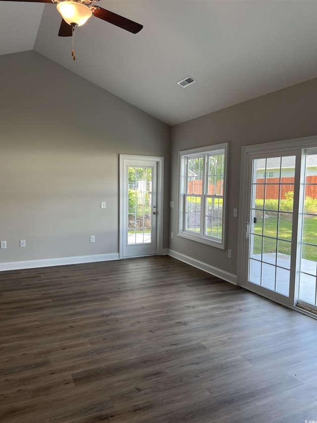 spare room featuring dark wood-style flooring, a ceiling fan, baseboards, vaulted ceiling, and visible vents