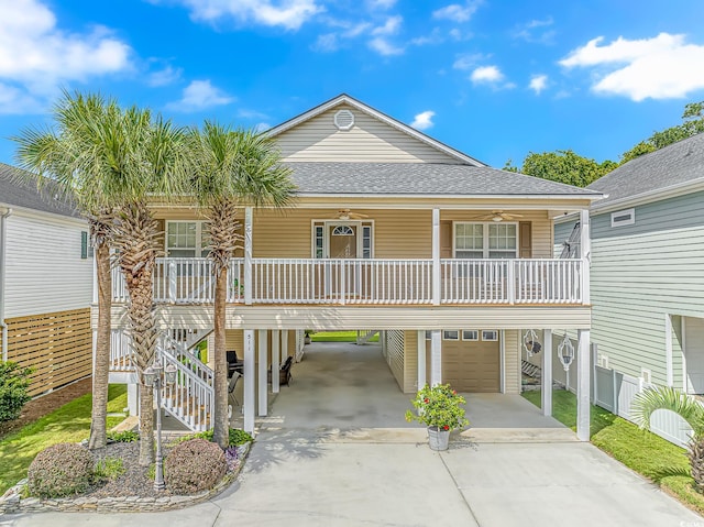 raised beach house featuring a porch, a shingled roof, stairs, a carport, and a garage