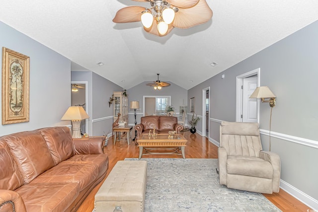 living area featuring baseboards, lofted ceiling, wood finished floors, and a ceiling fan