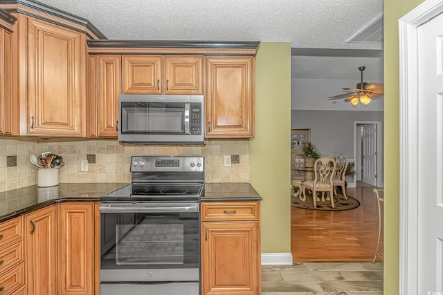 kitchen featuring light wood finished floors, decorative backsplash, appliances with stainless steel finishes, and a textured ceiling