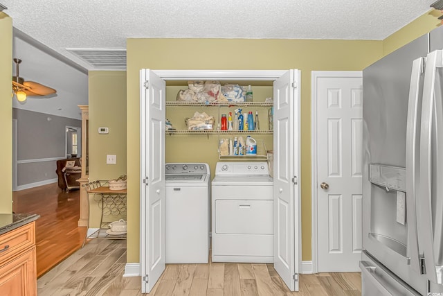 laundry room with laundry area, separate washer and dryer, light wood finished floors, and a textured ceiling