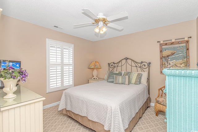 bedroom featuring visible vents, baseboards, light colored carpet, and a textured ceiling