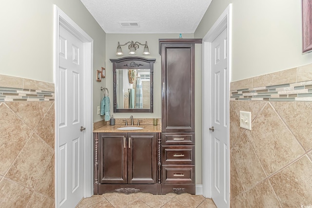 bathroom featuring tile walls, visible vents, tile patterned floors, and a textured ceiling