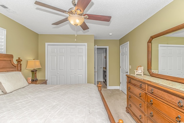 bedroom featuring visible vents, light carpet, a closet, a textured ceiling, and a ceiling fan