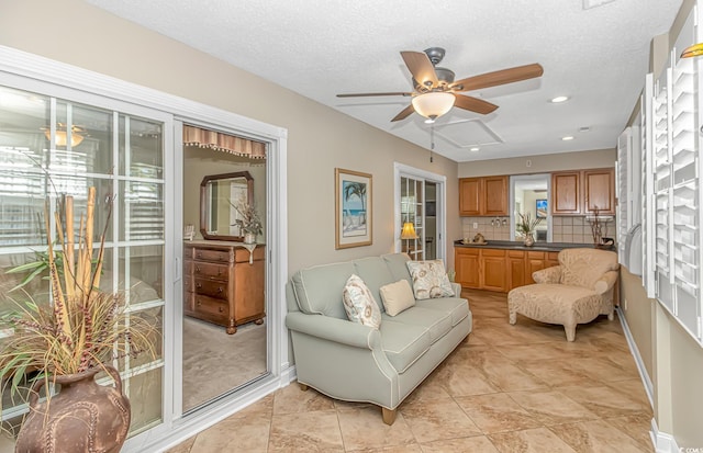 living area with a textured ceiling, recessed lighting, baseboards, and ceiling fan