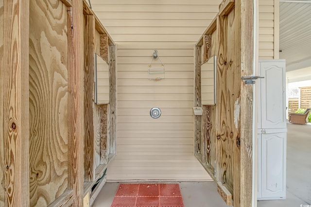 bathroom with concrete flooring and wood walls