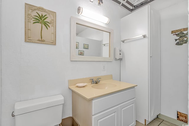 bathroom with toilet, vanity, and tile patterned flooring