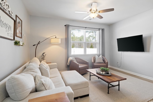 living area featuring ceiling fan, baseboards, and wood finished floors