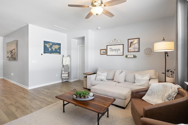 living area featuring light wood-style flooring, a ceiling fan, and baseboards