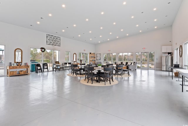 dining area featuring a high ceiling, healthy amount of natural light, finished concrete floors, and recessed lighting