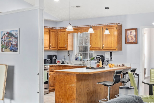 kitchen featuring stove, a peninsula, visible vents, light countertops, and a sink