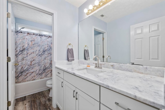 bathroom featuring a textured ceiling, vanity, visible vents, toilet, and wood finished floors