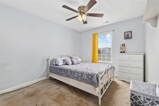 carpeted bedroom featuring a textured ceiling, baseboards, a ceiling fan, and visible vents