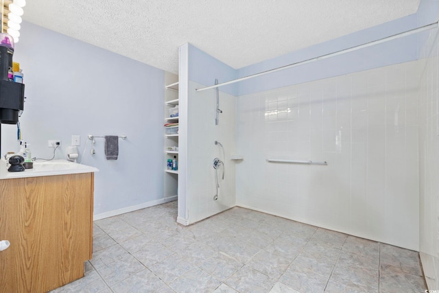 bathroom featuring a shower, a textured ceiling, and vanity