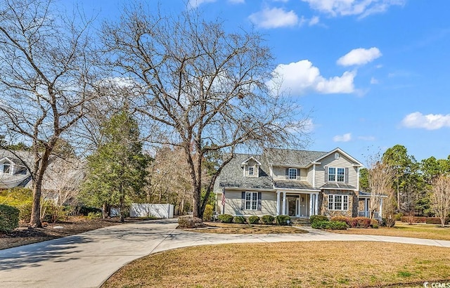 view of front facade featuring stone siding, driveway, and a front yard